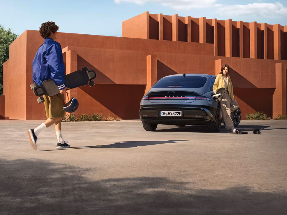 Žena naslonjena na bočnu stranu električne limuzine Hyundai IONIQ 6.